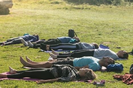 © Janice Mathues De deelnemers aan de yogasessie liggen in het gras.